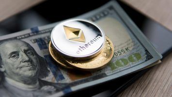 Ethereum coin on a us dollars and on the tablet with golden coins. Bitcoin crypto currebcy on US dollars. Digital currency. Virtual money. Metal coins of bitcoin on banknotes. Bussiness, commercial.